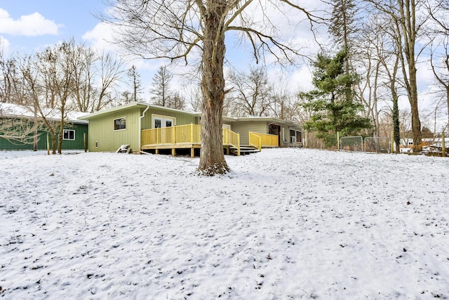 snow covered back of property featuring a wooden deck