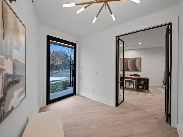 foyer entrance with an inviting chandelier and light hardwood / wood-style flooring