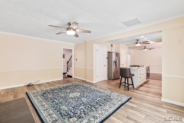 living room featuring light hardwood / wood-style floors, ornamental molding, and a textured ceiling