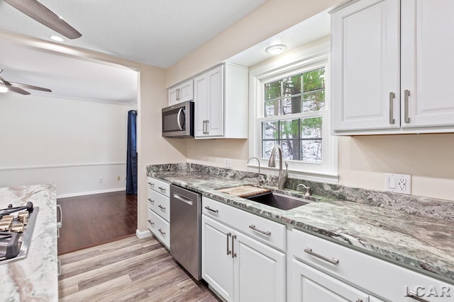 kitchen with ceiling fan, sink, stainless steel appliances, white cabinets, and light wood-type flooring