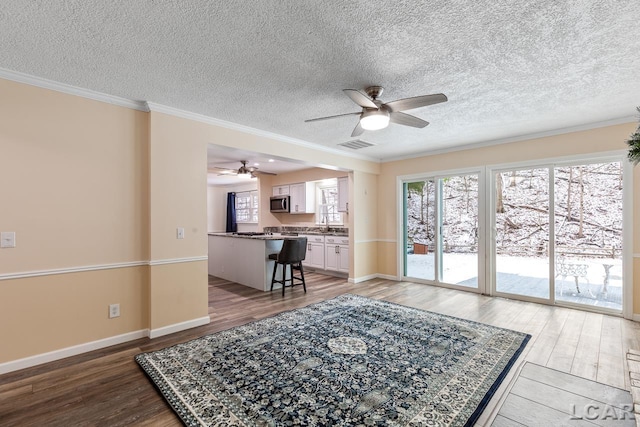 living room featuring hardwood / wood-style flooring, ornamental molding, and a textured ceiling