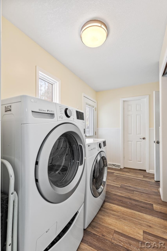 washroom with a textured ceiling, separate washer and dryer, and dark hardwood / wood-style floors