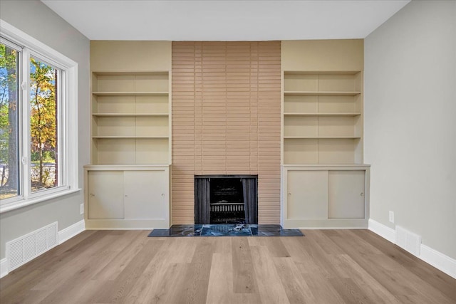 unfurnished living room featuring light wood-type flooring and a fireplace