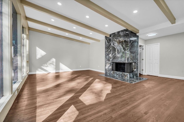 unfurnished living room featuring a high end fireplace, wood-type flooring, and beamed ceiling