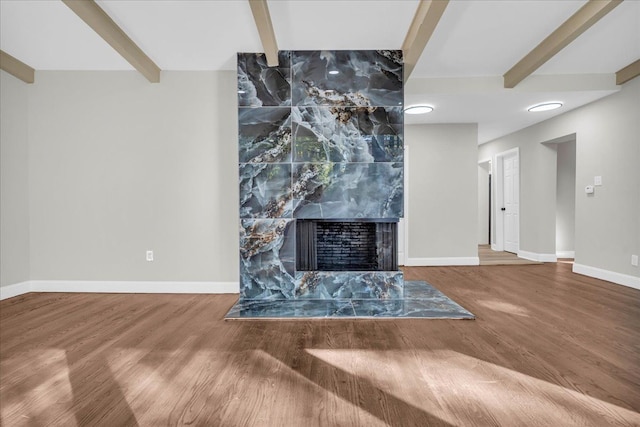 unfurnished living room featuring beam ceiling, a high end fireplace, and wood-type flooring