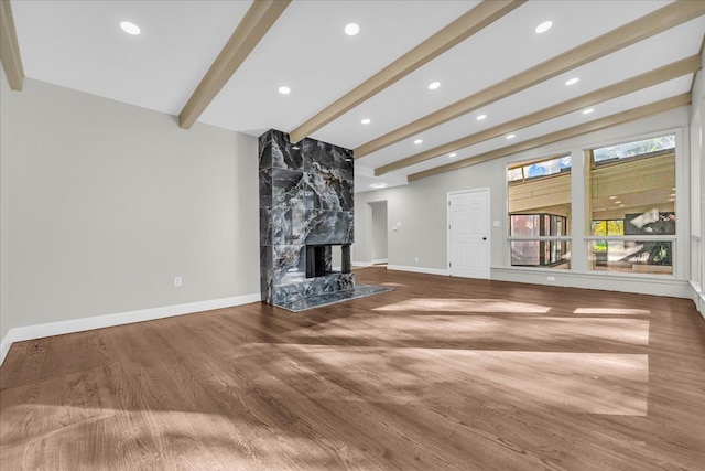 unfurnished living room with beamed ceiling, wood-type flooring, and a high end fireplace