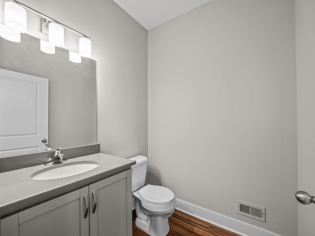 bathroom with wood-type flooring, vanity, and toilet