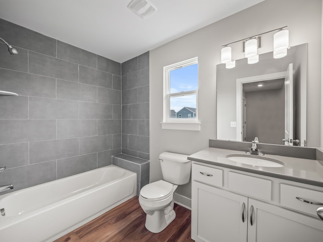 full bathroom featuring tiled shower / bath combo, toilet, wood-type flooring, and vanity