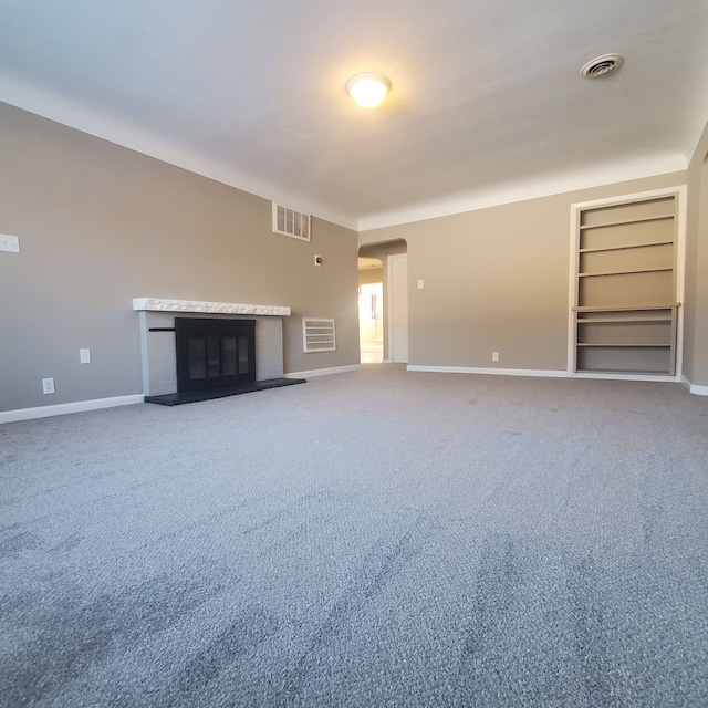 unfurnished living room featuring carpet flooring and built in shelves