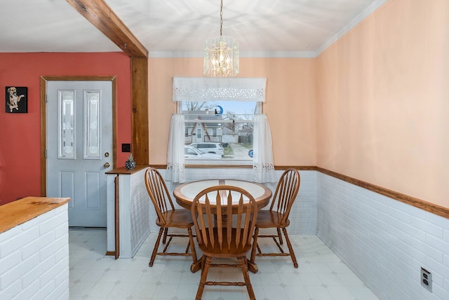 dining space with ornamental molding, tile walls, and an inviting chandelier