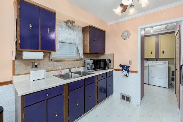 kitchen with sink, ceiling fan, separate washer and dryer, blue cabinetry, and tile walls