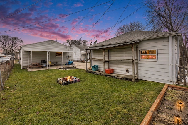 back house at dusk with a lawn, an outdoor fire pit, and a patio