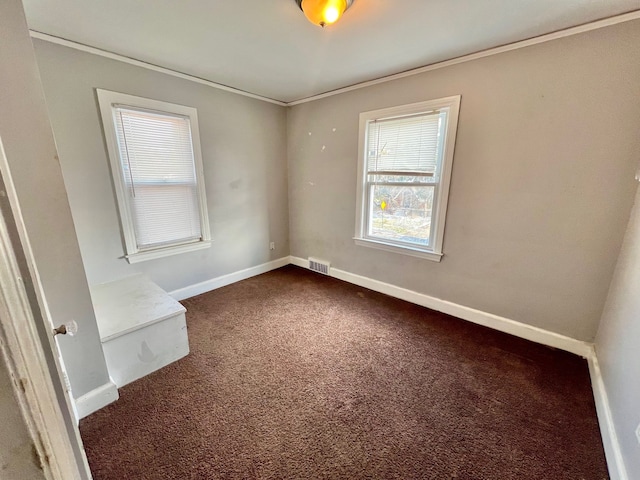 spare room with ornamental molding and dark carpet