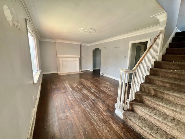 unfurnished living room featuring dark wood-type flooring and crown molding