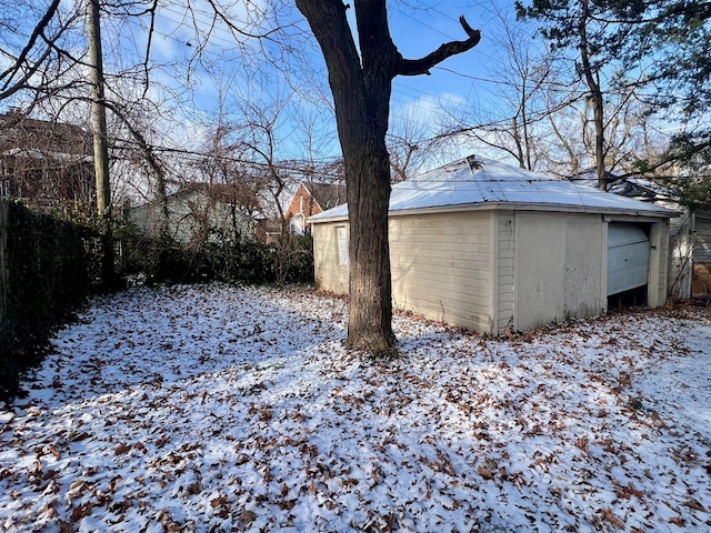 yard layered in snow featuring a garage and an outdoor structure