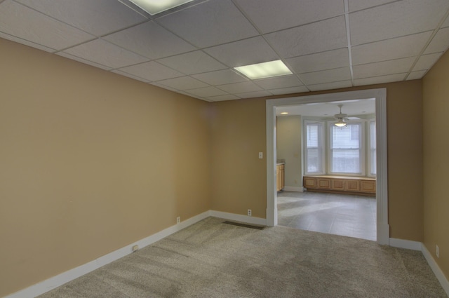 carpeted spare room with ceiling fan and a drop ceiling