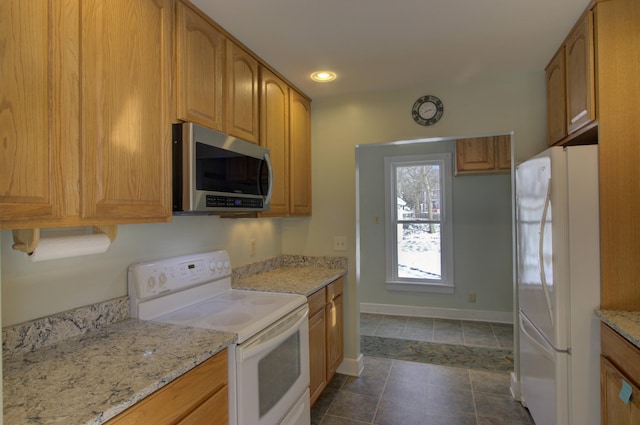 kitchen featuring light stone countertops, white appliances, and dark tile patterned flooring