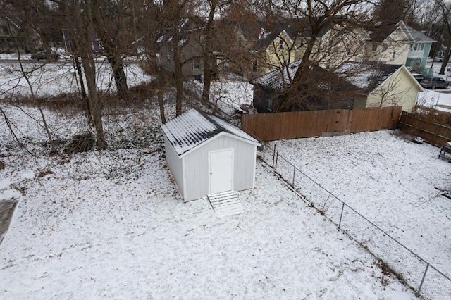 snowy yard featuring a storage shed