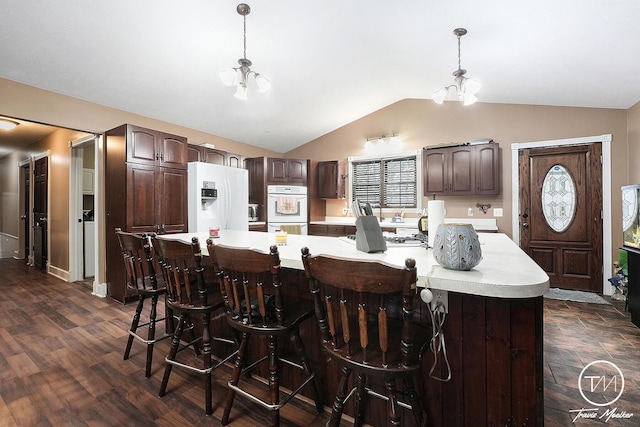 kitchen featuring a large island, a notable chandelier, vaulted ceiling, white appliances, and dark brown cabinets