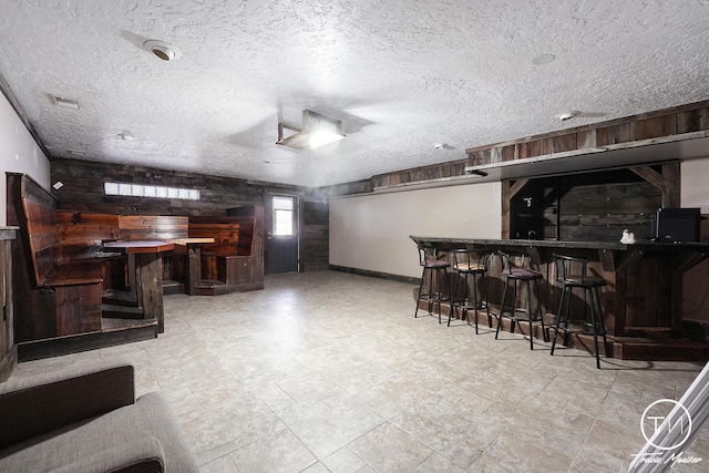 bar featuring a textured ceiling and wood walls