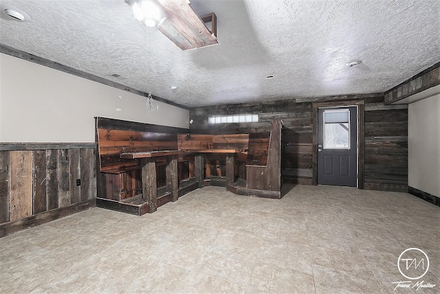 unfurnished living room featuring a textured ceiling and wooden walls