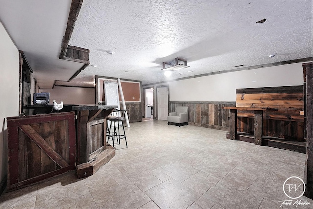 interior space featuring bar area, a textured ceiling, and wood walls