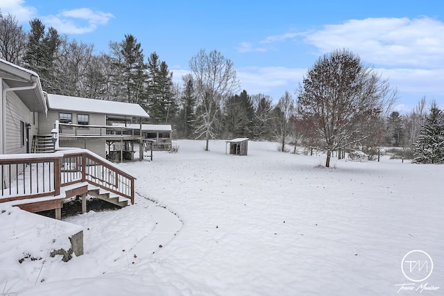 yard covered in snow with a storage unit and a deck