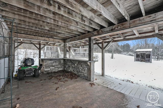 snow covered patio featuring a storage unit