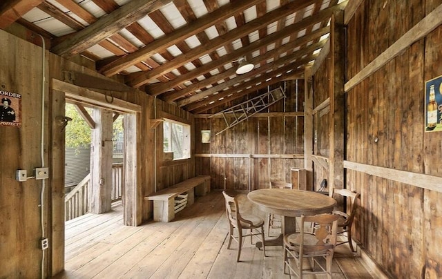 misc room with lofted ceiling with beams, light hardwood / wood-style flooring, and wood walls