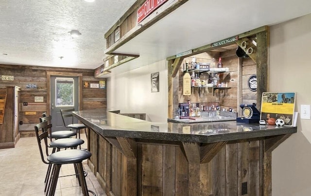 bar featuring wooden walls and a textured ceiling