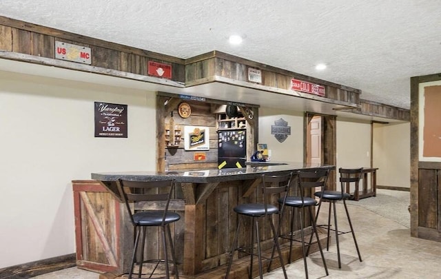 bar featuring black fridge and a textured ceiling