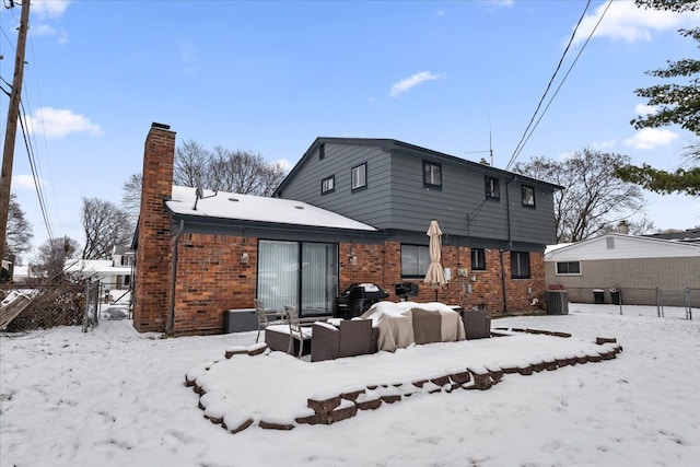 snow covered house featuring central AC unit