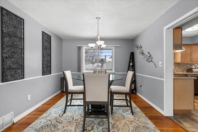 dining space featuring an inviting chandelier, a textured ceiling, and dark hardwood / wood-style floors