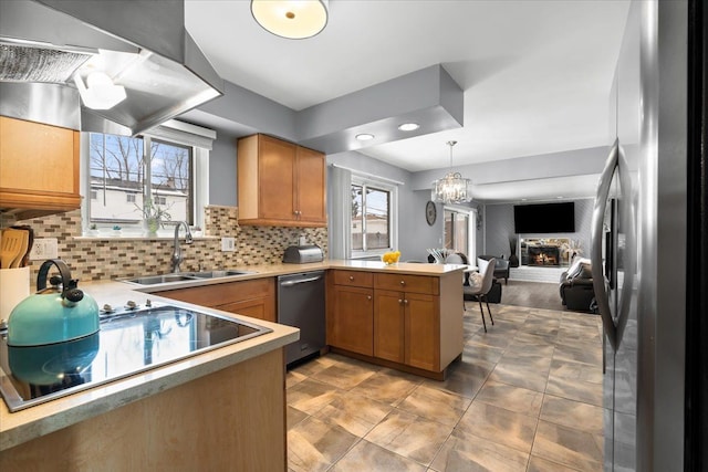 kitchen with kitchen peninsula, a healthy amount of sunlight, decorative backsplash, appliances with stainless steel finishes, and sink