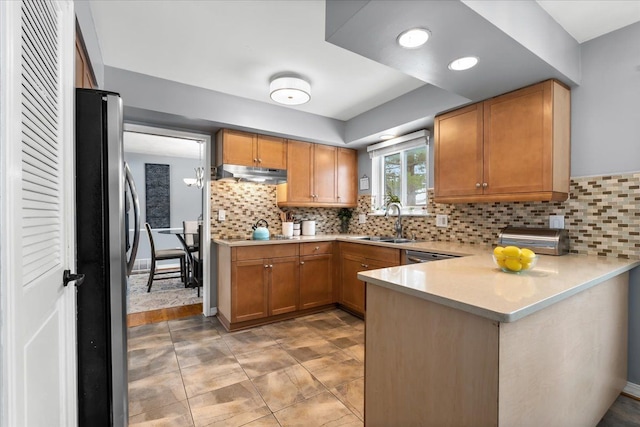 kitchen featuring sink, tasteful backsplash, kitchen peninsula, and stainless steel refrigerator