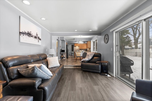 living room with light wood-type flooring, an inviting chandelier, and crown molding