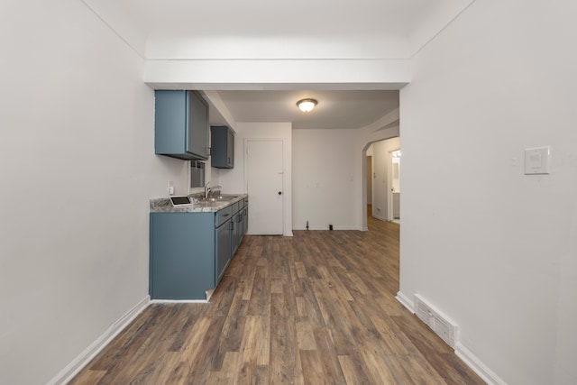 kitchen with blue cabinetry, dark hardwood / wood-style flooring, and sink