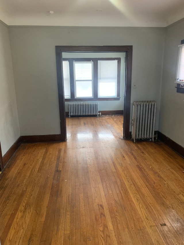 empty room with radiator heating unit and hardwood / wood-style flooring