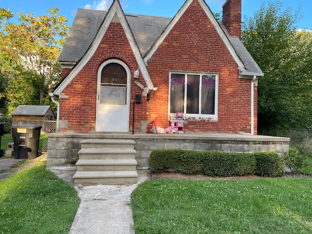 tudor-style house featuring brick siding and a chimney