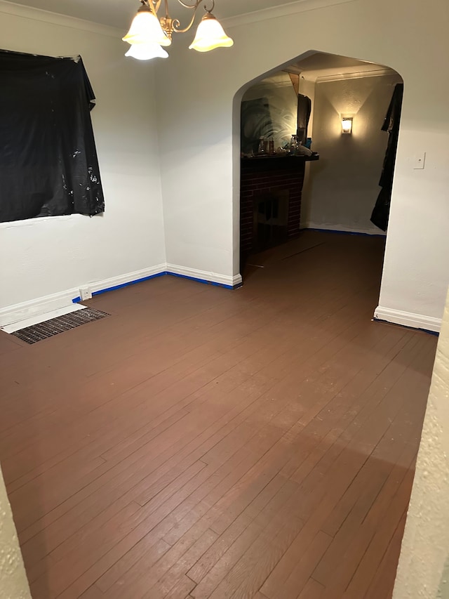 spare room featuring baseboards, ornamental molding, hardwood / wood-style floors, and a notable chandelier