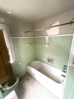 bathroom featuring tile patterned flooring, tiled shower / bath combo, and toilet