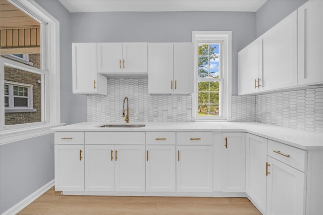 kitchen featuring tasteful backsplash, white cabinetry, and sink