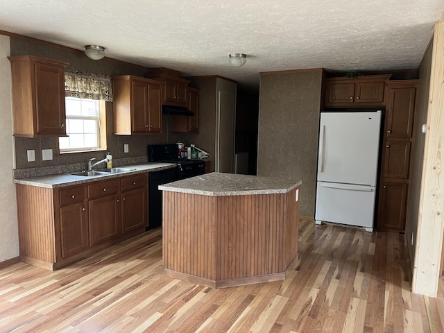 kitchen with a center island, black appliances, sink, light wood-type flooring, and a textured ceiling