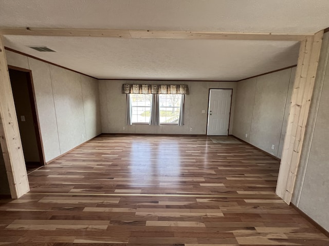 spare room featuring beam ceiling, a textured ceiling, and hardwood / wood-style flooring