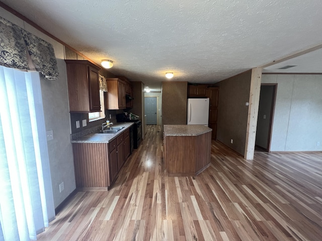 kitchen featuring black / electric stove, white refrigerator, a kitchen island, and light hardwood / wood-style flooring