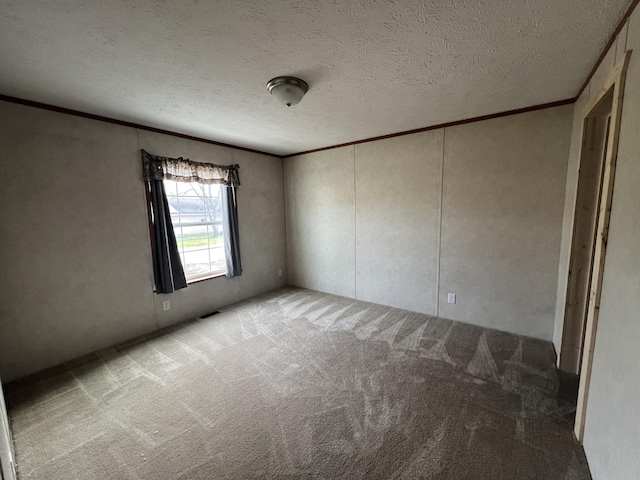 empty room featuring carpet, ornamental molding, and a textured ceiling