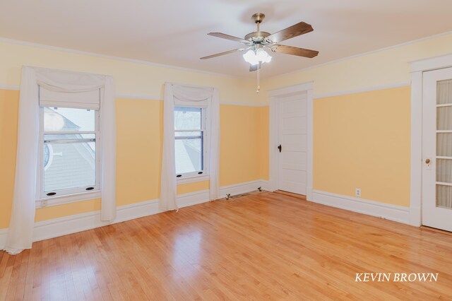 empty room featuring ceiling fan, baseboards, wood finished floors, and crown molding