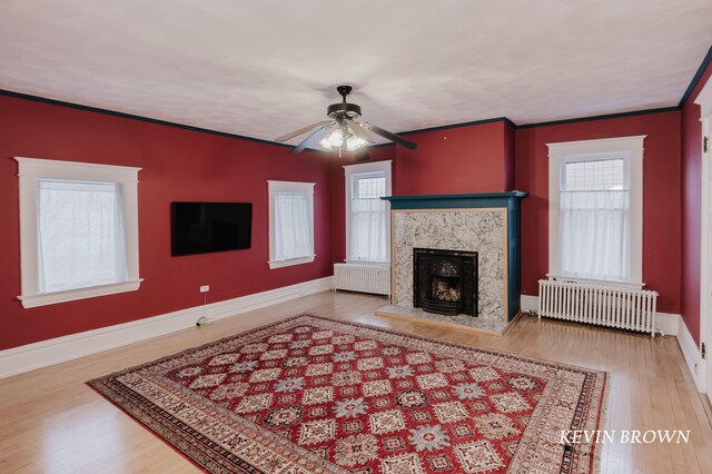 living area featuring a premium fireplace, radiator, wood finished floors, and ornamental molding