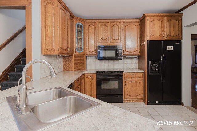 kitchen featuring black appliances, light countertops, backsplash, and a sink