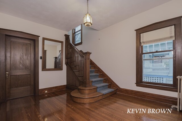 stairs featuring a wealth of natural light, radiator heating unit, baseboards, and wood finished floors